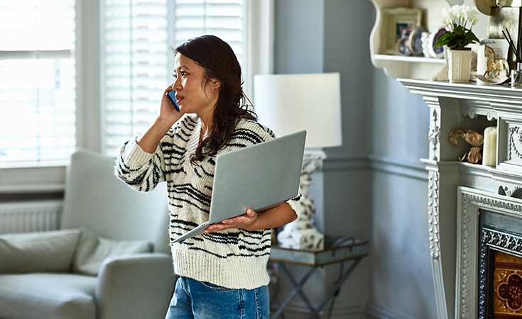 woman talking on the phone while holding a laptop
