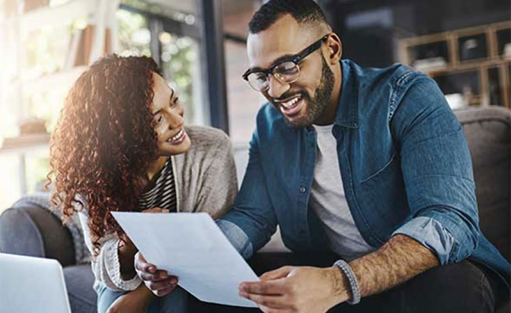 black couple smiling and looking at a piece of paper