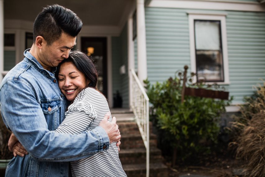 Couple hugging in front of a house