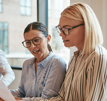 two women wearing glasses and looking at a piece of paper together
