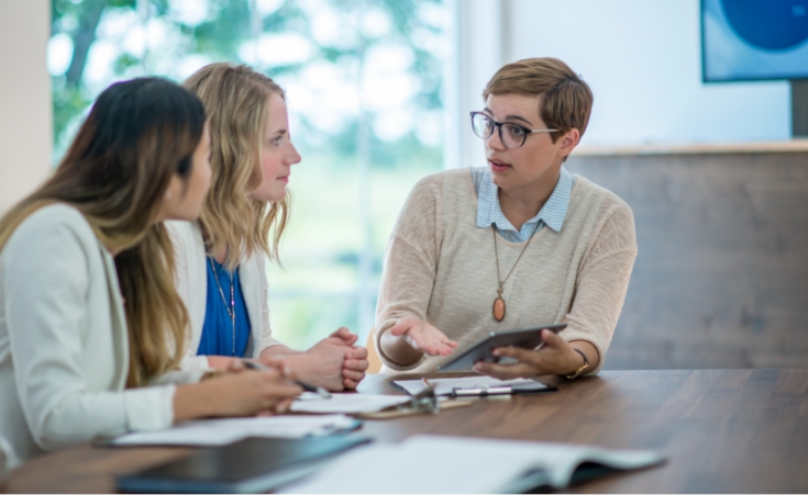 a female financial professional sitting down and talking with two women