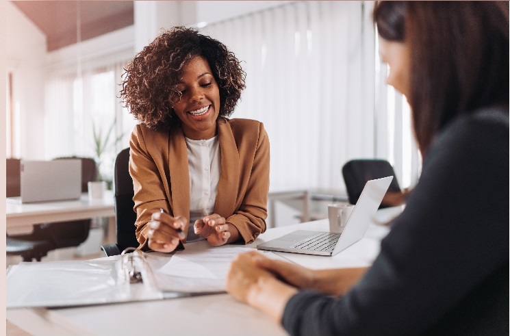 black professional woman smiling while meeting with a white woman