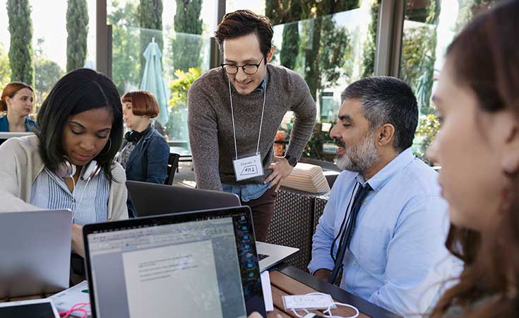 group of coworkers gathered around a desk talking
