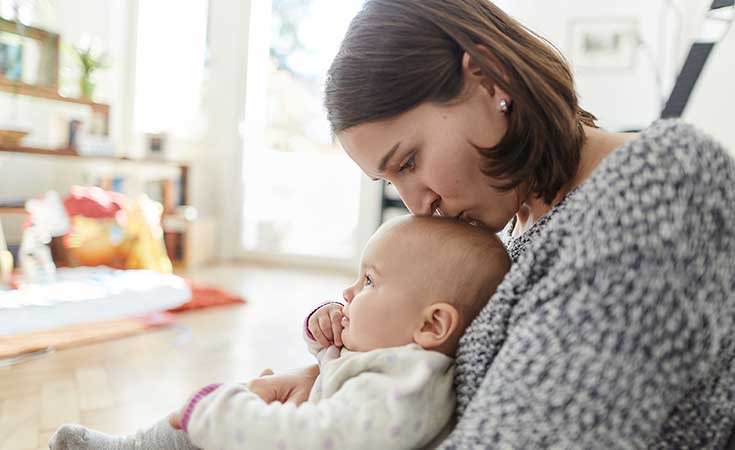 mother kissing top of baby's head