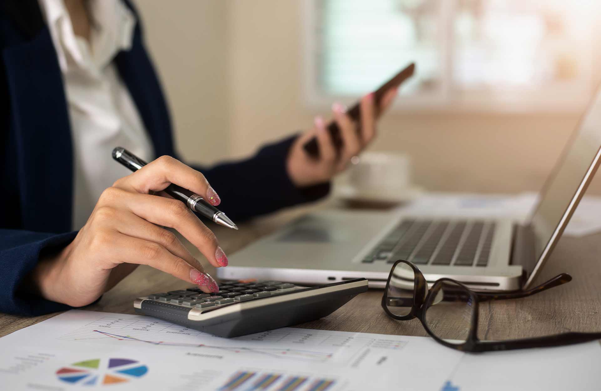 woman's hands using calculator and phone