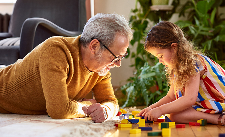 Father and daughter playing with blocks on the floor.